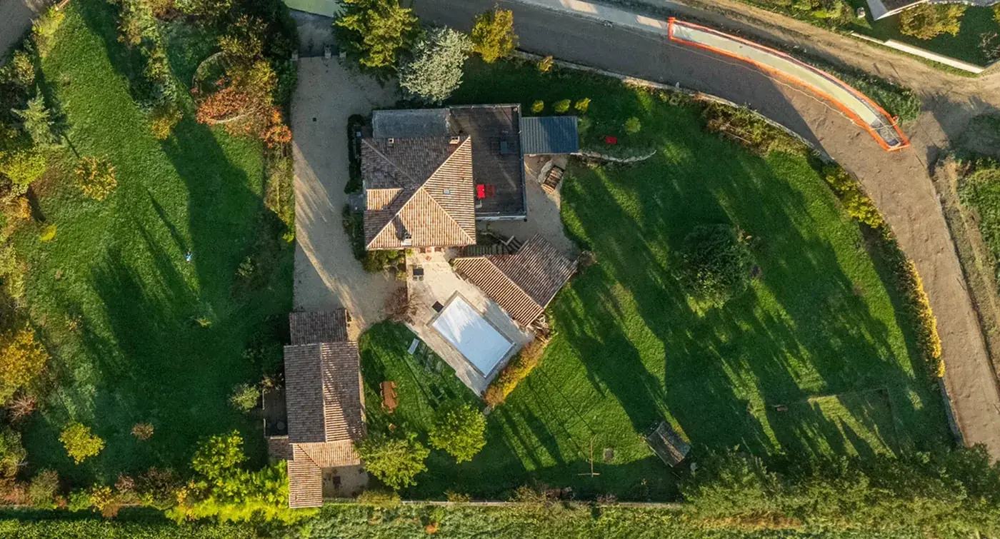 Vue aérienne du domaine de La Pradella : la bâtisse en pierre, la piscine et le jardin clos en Ardèche Verte
