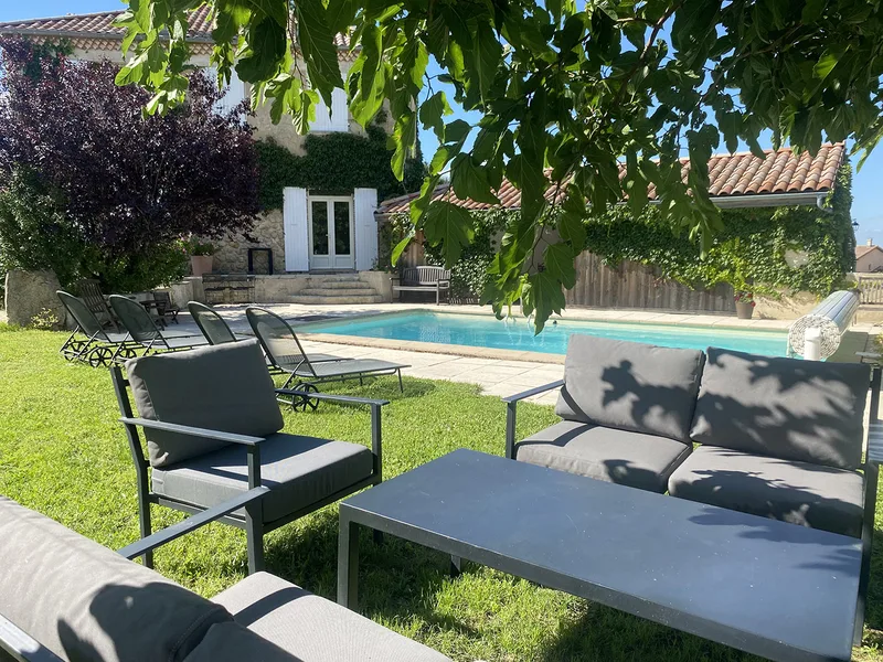 Le salon lounge sous un arbre, face à la piscine de La Pradella et à la bâtisse en pierre
