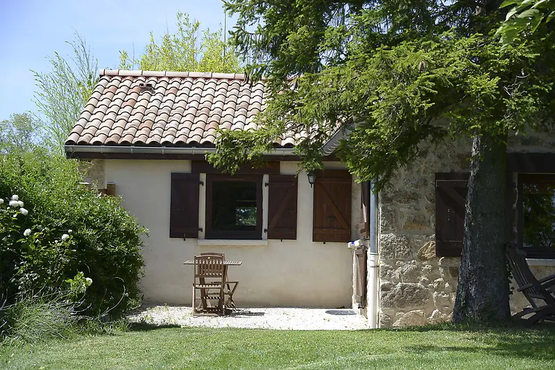 Un petit cottage en pierre aux volets bois, à l'ombre dans le jardin de La Pradella