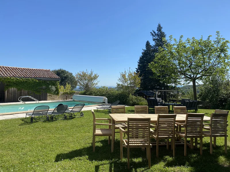 La table de jardin en teck et les transats au bord de la piscine de La Pradella, vue sur les collines