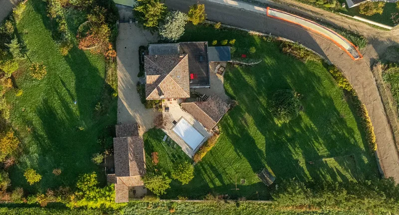 Vue aérienne du domaine de La Pradella : la bâtisse en pierre, la piscine et le jardin clos en Ardèche Verte