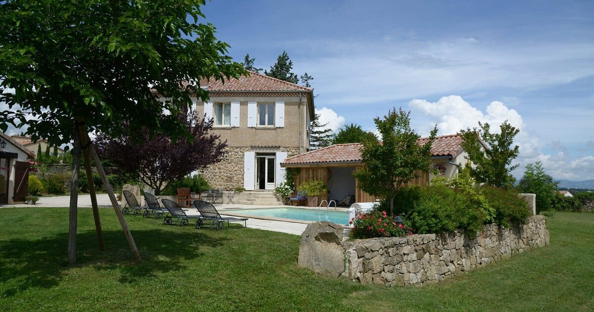La grande table en teck sur la terrasse de La Pradella, devant la façade en pierre et ses lavandes