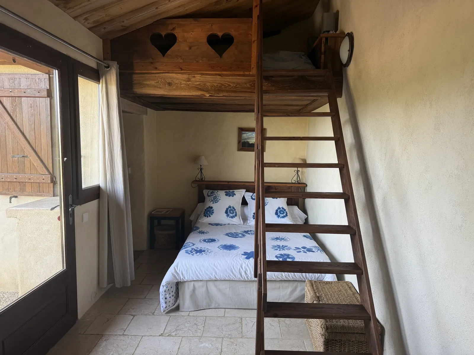 Le Lavoir : le lit double habillé de toile bleue et sa mezzanine en bois, accessible par une échelle de meunier