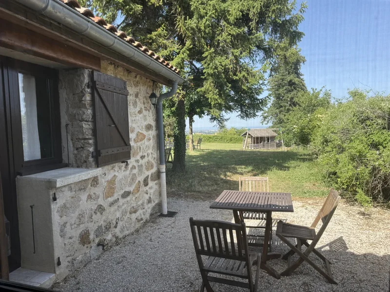 Le Lavoir : la terrasse privative en pierre et sa table, ouverte sur le jardin et la campagne