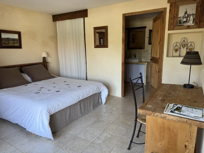 L'Hirondelle : la chambre aux murs à la chaux, avec son lit double et sa porte en bois ancien