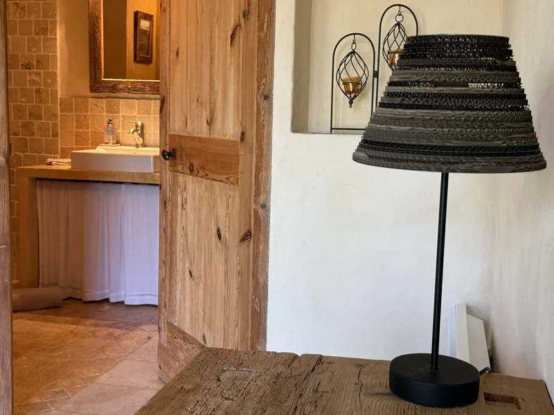 L'Hirondelle : la lampe en carton de l'atelier posée sur un meuble en vieux bois